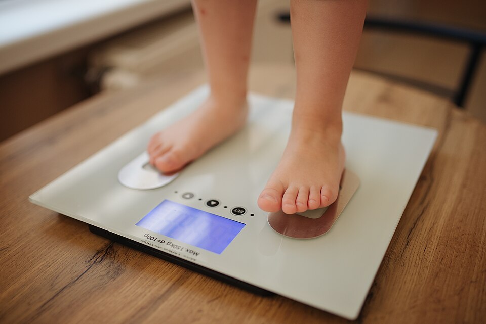960px Girl stands and weighs himself on white modern electronic smart scale 51258015258